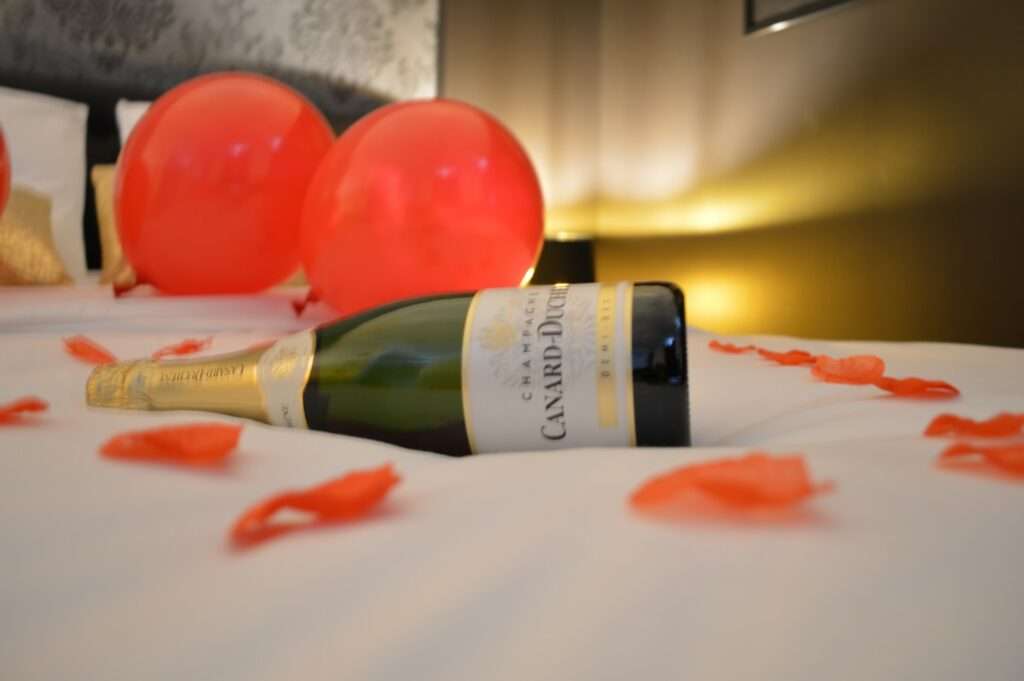 bouteille de Champagne, ballon rouge et pétales de rosessur le lit
