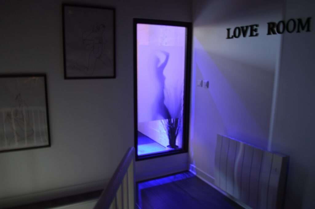 jeux de lumière provenant de la douche avec inscription "love room" sur le mur